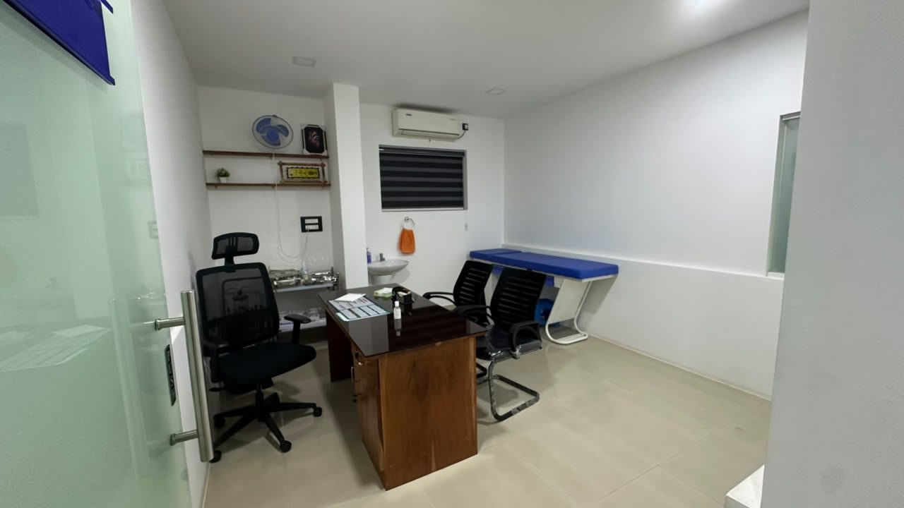 A consulting room with a desk, chairs and examination couch
