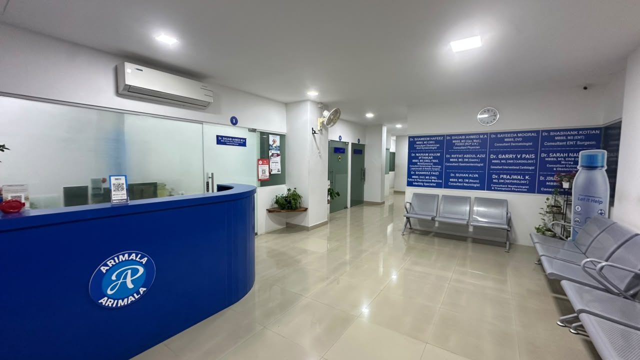 The reception desk at Arimala Polyclinic, with waiting chairs and the doctors&rsquo; name boards behind